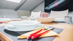 A dining area with a table set for two, including plates, cutlery, and glasses. - Vrbo Property (Torino)
