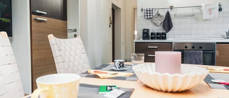 A modern kitchen with a dining area, including a table with a placemat, a candle, and a coffee machine.