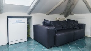 A small room with a white refrigerator, a dark leather sofa, and a tiled floor. - Vrbo Property (Torino)
