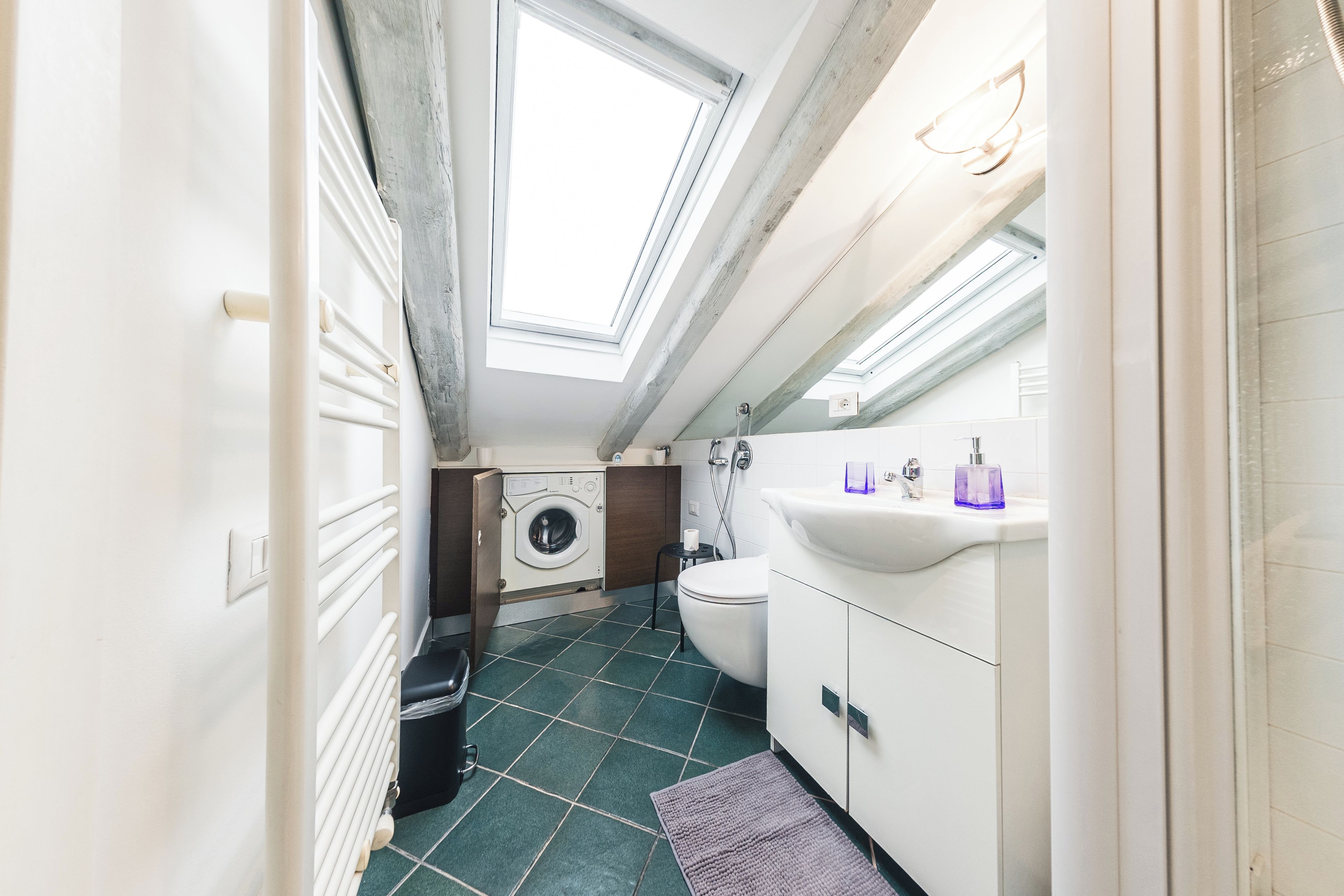Ein kleines Badezimmer mit Oberlicht, Waschmaschine, Toilette und Waschbecken.
