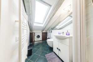 Un bagno compatto con una finestra a lucernario, una lavatrice, un water e un lavandino.