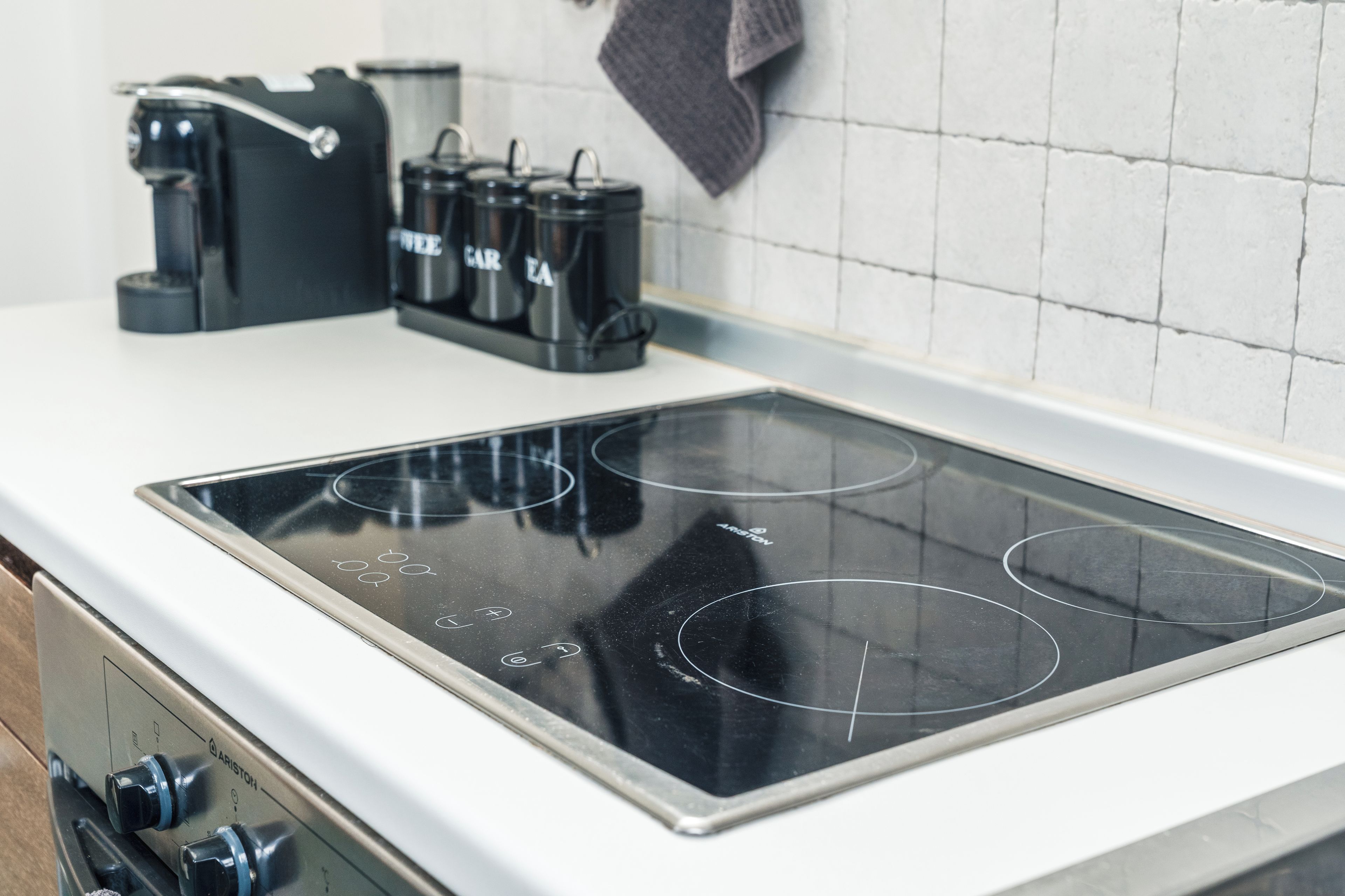 A kitchen with a black induction cooktop, a coffee maker, and a kettle.
