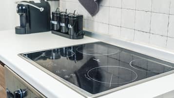 Una cucina con un piano cottura a induzione nero, una macchina del caffè e un bollitore.