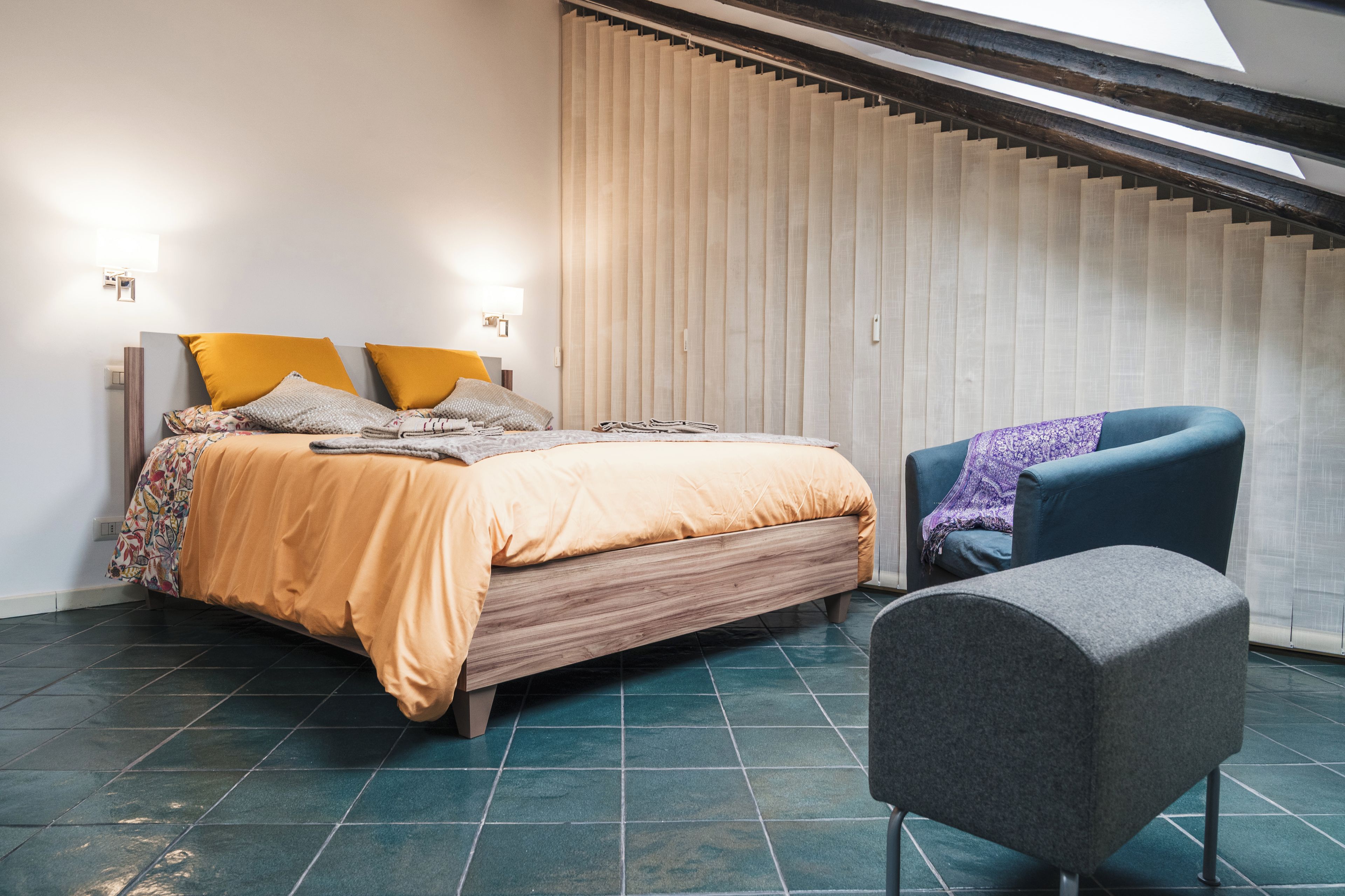 Ein Schlafzimmer mit einem Bett, einem Sessel und einem Fenster mit Jalousien.