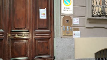 Una porta in legno con una soglia in ottone, un segnale di divieto di parcheggio e un sistema di citofono di sicurezza.