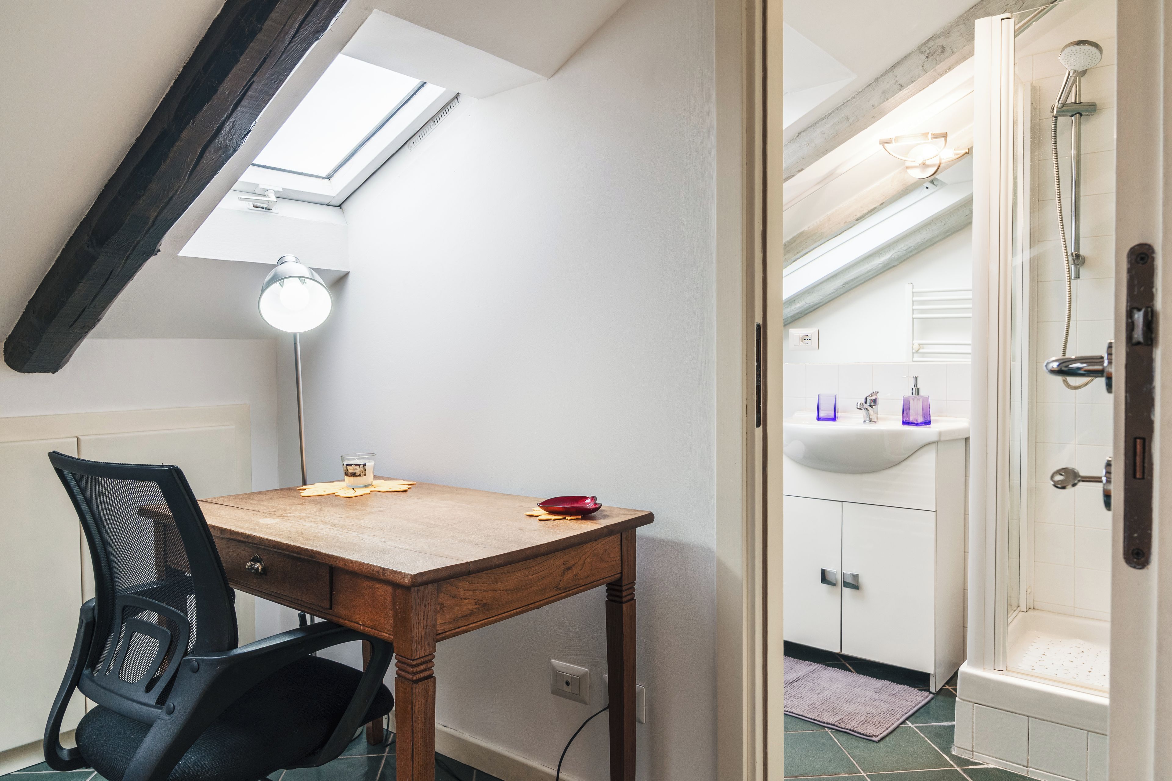 Ein Zimmer mit Schreibtisch, Stuhl und Dachfenster.
