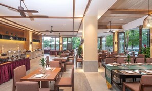 A restaurant with multiple dining tables, ceiling fans, and large windows offering a view of the outdoors. - South China (Sanya)
