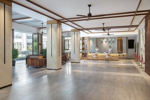 A modern hotel lobby with a reception desk, seating area, and large windows. - South China (Sanya)