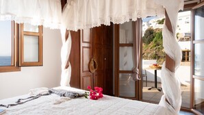 A bedroom with a bed, a window, a door, and a view of the outside. - Panteli Beach (Leros)