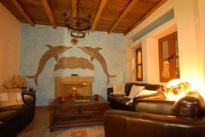 Una sala de estar con chimenea, muebles de cuero y un mural en la pared.
