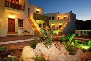 Edificio de dos pisos con una escalera que conduce al nivel superior, rodeado de jardines ajardinados.