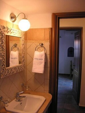 Un baño con lavamanos, espejo, toallero e iluminación.