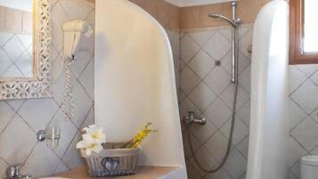 A bathroom with a sink, a mirror, a shower, and a toilet.