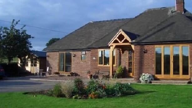 A two-story brick house with a pitched roof, a front porch, and a satellite dish. - Dove Meadow (Uttoxeter)