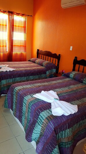 Une chambre avec deux lits, chacun étant recouvert d’une courtepointe à rayures et muni d’un oreiller.