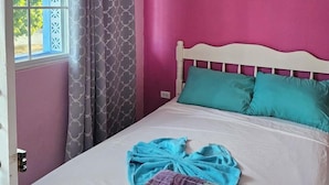 A room with a bed, a window with curtains, and a door. - Anchorage Resort (Caye Caulker)