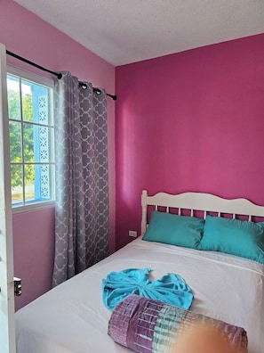 Une pièce avec un lit, une fenêtre avec des rideaux et une porte.
