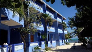 A multi-story hotel with balconies, a beach view, and palm trees. - Anchorage Resort (Caye Caulker)