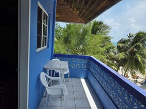 A balcony with a blue railing, a white table, and two white chairs. - Anchorage Resort (Caye Caulker)