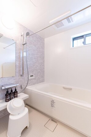 Une salle de bain moderne avec une baignoire blanche, des toilettes et un meuble-lavabo avec des flacons.