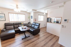 Un salon moderne avec un canapé d’angle, une table à manger et un ventilateur de plafond.