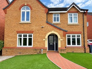 A two-story house with a brick facade, a black front door, and a paved driveway leading to the entrance. - 4-Bedroom Home | Fully Equipped | Waverley (Catcliffe)