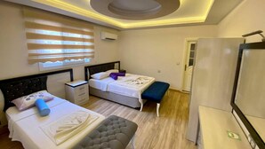 A hotel room with two beds, a bench, a TV, and a circular ceiling light. - Erkan Tumen Yalcin Hotel (Fethiye)