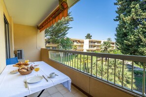 Un balcon avec une table préparée pour le petit-déjeuner, comprenant du pain, des fruits et un verre de jus.