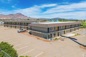 A two-story motel with a parking lot and a mountain backdrop.