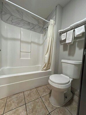 A bathroom with a bathtub, toilet, and a shower curtain.