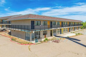 A multi-story motel with a flat roof, a parking lot, and a small landscaped area with gravel and plants. - Signature Inn Socorro (Socorro)