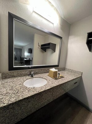 A bathroom with a granite countertop, a sink, a mirror, and a towel dispenser. - Gazelle Stay by Hotel O Socorro (Socorro)