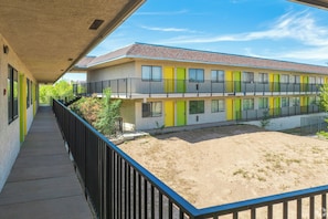 A multi-story building with balconies, a covered walkway, and a sandy courtyard. - Signature Inn Socorro (Socorro)
