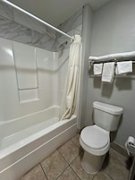 A bathroom with a bathtub, toilet, and a shower curtain.