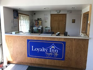 Balcão de recepção em hotel com placa indicando 'Loyalty Inn Simply Stay'.