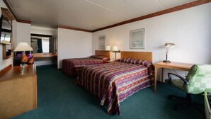 Hotellihuone, jossa on kaksi sänkyä, työpöytä, tuoli ja peili.