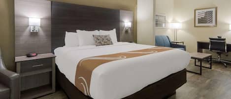 Una habitación de hotel con una cama grande, mesitas de noche, un escritorio y una silla.