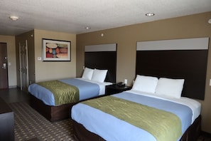 Quarto de hotel com duas camas, um quadro na parede e uma porta.
