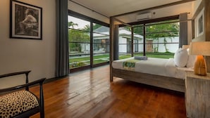 Ein Schlafzimmer mit einem Bett, einem Sessel, einem Fenster und einem gerahmten Bild an der Wand.