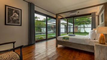 A bedroom with a bed, a chair, a window, and a wall-mounted picture.