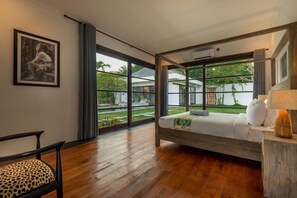 Um quarto com cama, uma cadeira, uma janela e um quadro na parede.