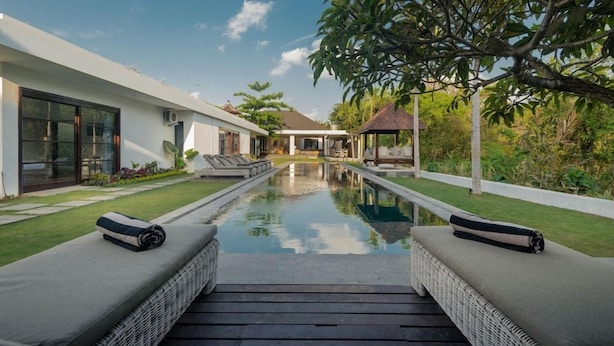 Ein moderner Poolbereich mit Liegestühlen und freiem Blick auf das Haus.