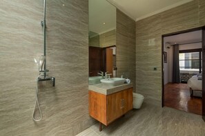 Uma casa de banho moderna com um espelho grande, chuveiro e sanita.