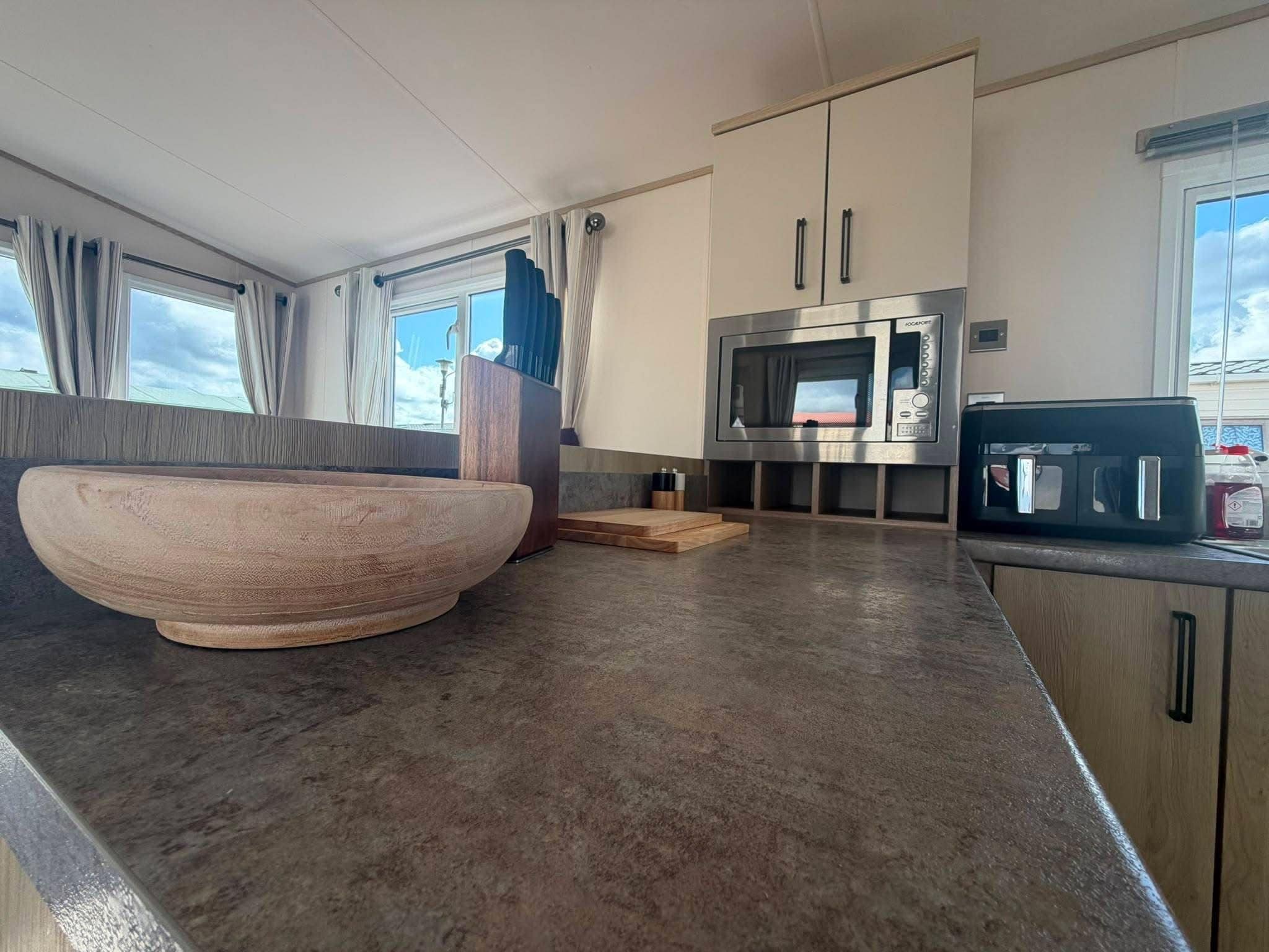 Una cocina moderna con un tazón de madera grande, un microondas y una máquina de café.