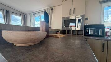 Una cocina moderna con un tazón de madera grande, un microondas y una máquina de café.