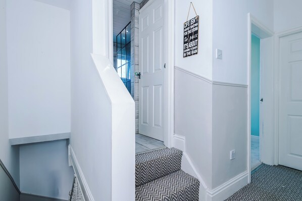 Ein Flur mit einer Treppe, einer Tür mit einem Schild und einem gemusterten Teppich.
