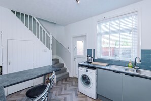 A compact kitchen with a built-in washing machine, a sink, and a window with blinds. - 2 Bed House Rochdale Free Parking (Rochdale)