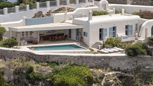 A white villa with a swimming pool, outdoor seating, and a stone retaining wall. - Belvedere Waterfront Villa and Suites (Mykonos)