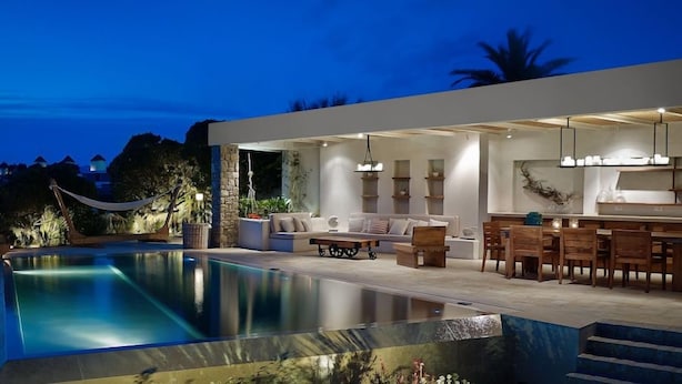 A modern outdoor living area with a pool, seating, and a bar. - Belvedere Waterfront Villa and Suites (Mykonos)