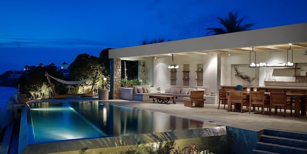 Ein moderner Außenbereich mit Pool, Sitzgelegenheiten und Bar.